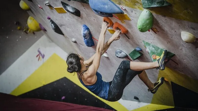 A climber working a problem on an indoor bouldering wall