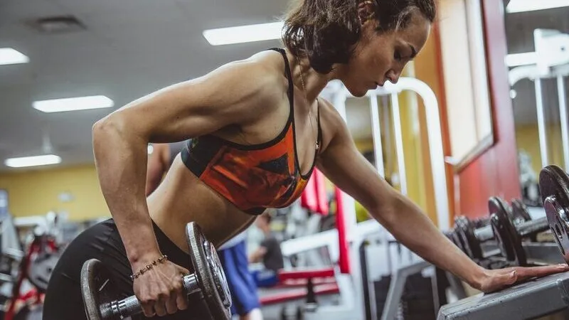 A member working through a dumbbell set on the gym floor