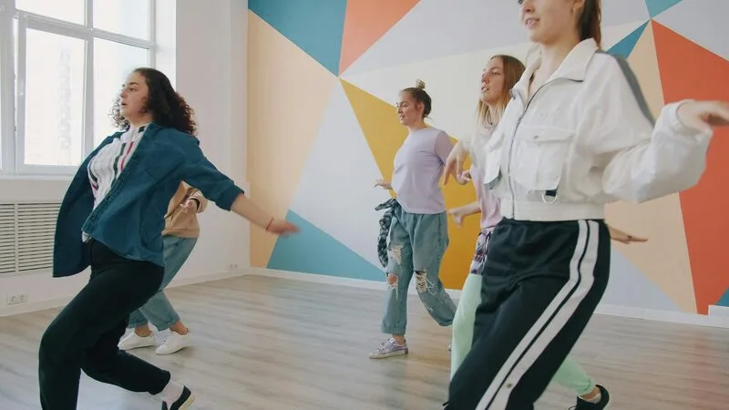 A group learning choreography together in a bright dance studio