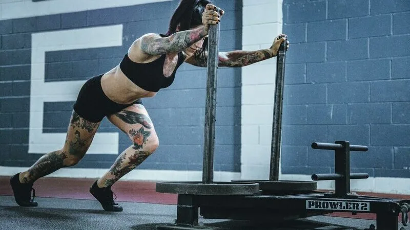 An athlete pushing a weighted sled across a gym floor