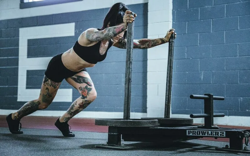 An athlete pushing a weighted sled across a gym floor