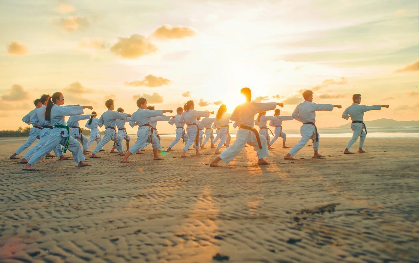 A karate class practising punches in a line at sunset