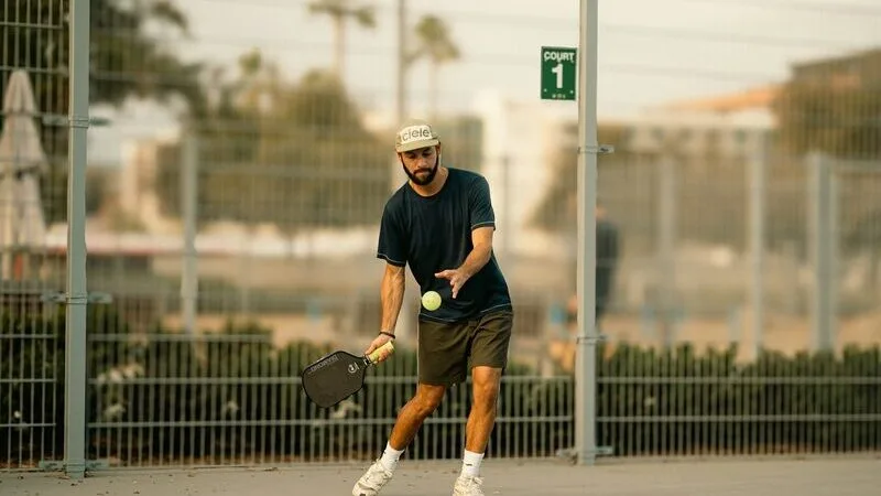 A pickleball player about to serve on an outdoor court