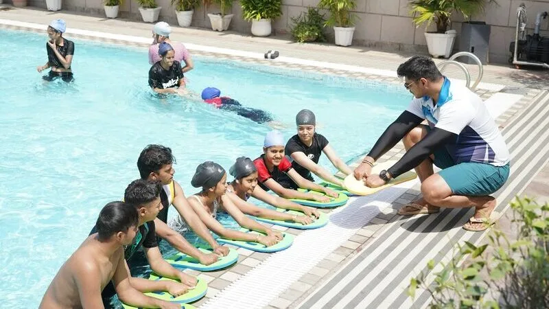 A coach running a swim lesson at the edge of the pool