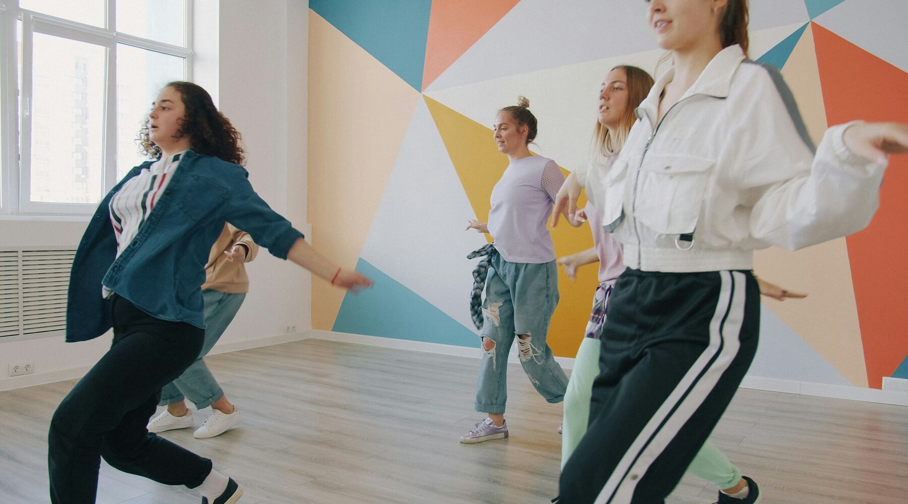 A group learning choreography together in a bright dance studio