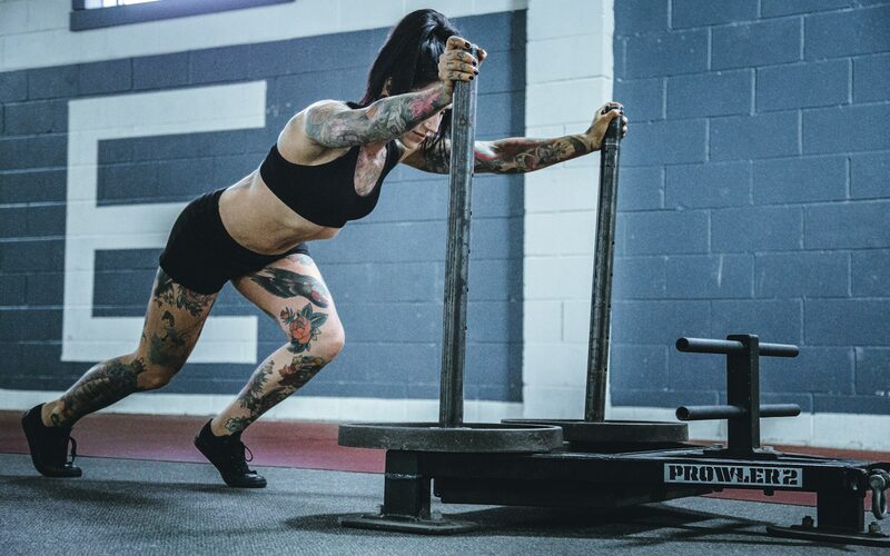 An athlete pushing a weighted sled across a gym floor
