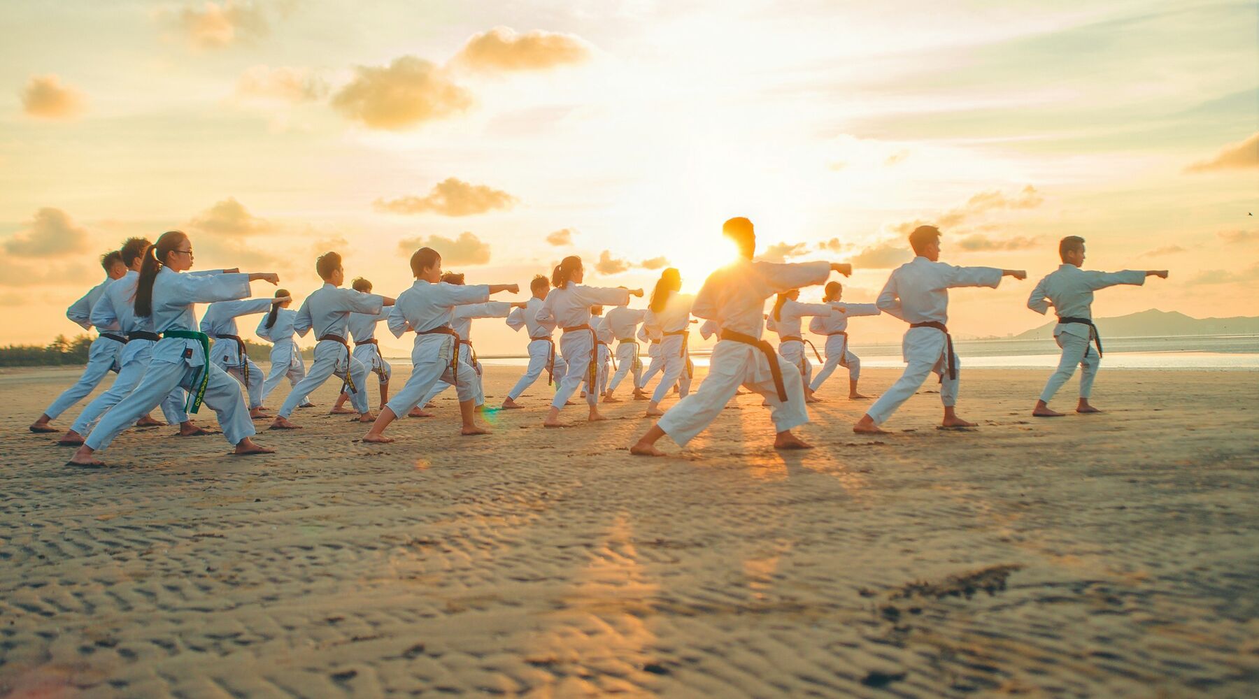 A karate class practising punches in a line at sunset