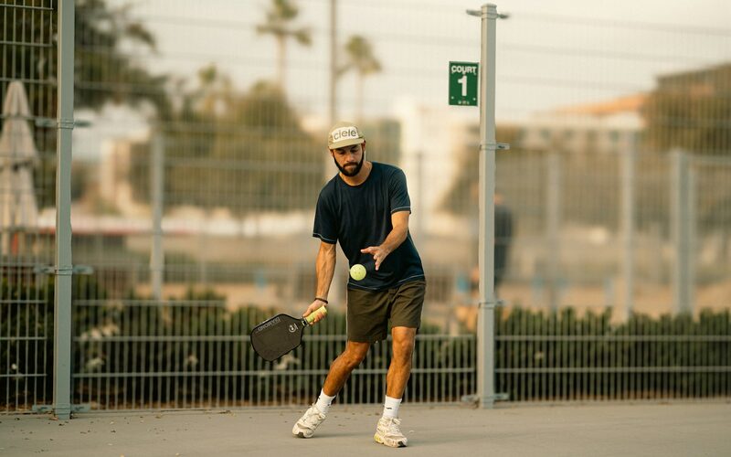 A pickleball player about to serve on an outdoor court