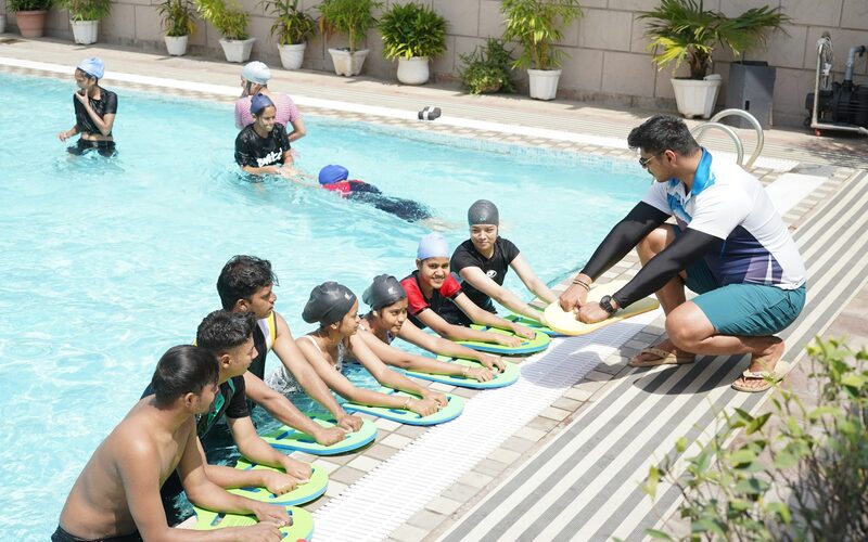 A coach running a swim lesson at the edge of the pool