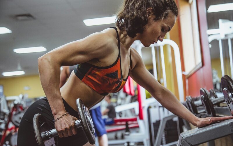 A member working through a dumbbell set on the gym floor